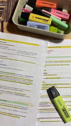 several markers and pens sitting on top of a paper next to a pen holder with papers