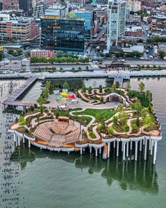 an island in the middle of water surrounded by tall buildings and lots of greenery