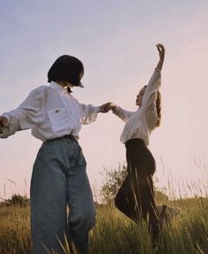 two people standing in tall grass holding hands