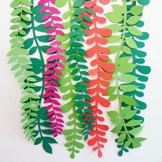 paper leaves are arranged on a white surface with pink, green and red colors in the background