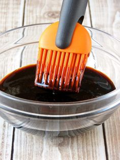 a brush is being used to clean the chocolate sauce in a glass bowl on a wooden table