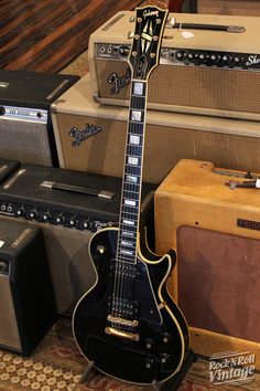 an electric guitar sitting on top of a rug next to other guitars and amps