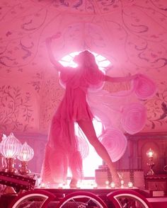 a woman in pink dress standing on top of a table