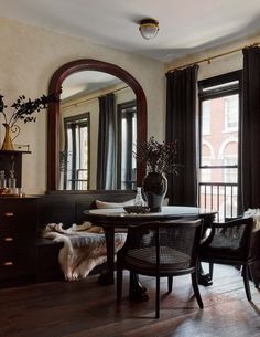 a dining room table and chairs in front of large windows