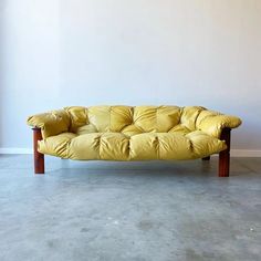 a yellow couch sitting on top of a cement floor next to a white wall in an empty room