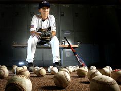 a baseball player sitting in the dugout with his bat and ball on the ground