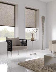 a living room filled with furniture and windows covered in roman blind shades on top of them