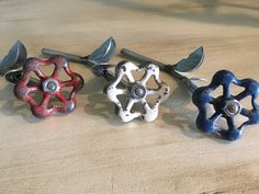 three different colored flower shaped knobs sitting on top of a wooden table next to each other