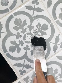 a person is using a knife to paint a wall with black and white designs on it