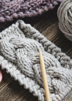 yarn and knitting needles sitting on top of a wooden table