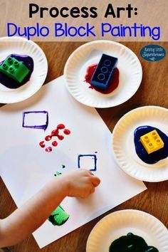 a child's hand is drawing on paper with lego blocks