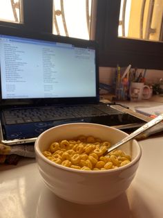 a bowl of cereal sits in front of a laptop