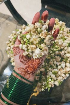 a woman's hand with henna and flowers on it