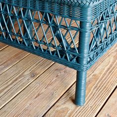 a blue wicker basket sitting on top of a wooden floor next to a table