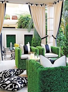 a living room filled with lots of green furniture and plants on top of the couches