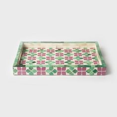 a green and pink patterned tray on a white surface