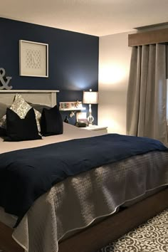 a bedroom with blue walls and white bedding, black and silver decor on the headboard