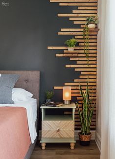 a bed room with a neatly made bed next to a night stand and a plant