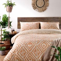 a bed with an orange and white bedspread next to potted plants on the floor