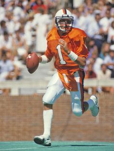 a football player running with the ball in his hand and people watching from the stands