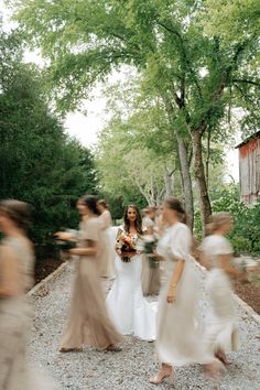 a group of women walking across a gravel road