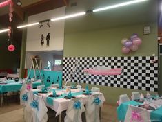 the tables are decorated with blue and white tablecloths, pink and purple balloons, and black and white checkered wallpaper