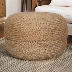 a large round jute ottoman sitting on top of a rug next to a white chair