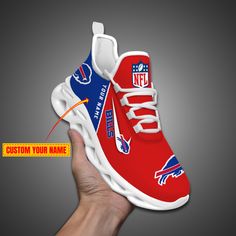 a hand holding a red and blue shoe with the new york giants logo on it