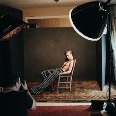 a woman sitting on a chair in front of a camera set up for a photo shoot