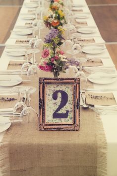 the table is set for two people with plates and silverware on it, along with a number 2 sign