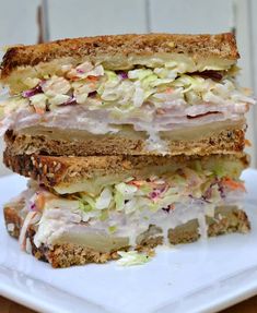 two halves of a sandwich stacked on top of each other with coleslaw and mayonnaise