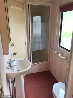 a bathroom with a sink, toilet and shower stall in the corner next to a window