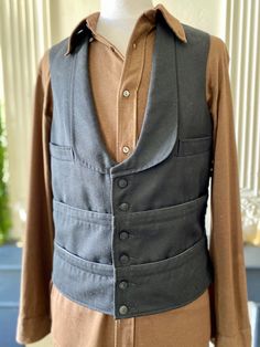 Authentic black French waiter's vest, multi-pocket, in thick cotton on the front and fine satin synthetic on the back. 8 pockets in bands around the waist, 2 chest pockets, 1 inside pocket, black glass buttons (probably not original but old nonetheless, maybe even older than the piece itself), rounded tuxedo collar at the bottom, adjustable tab with a metal buckle at the back. It is vintage without a doubt but for many classic pieces like certain work uniforms, it is difficult to date it precise Cotton Workwear Vest With Multiple Pockets, Cotton Work Vest With Multiple Pockets, Vintage Workwear Vest With Pockets, Vintage Vest With Pockets For Work, Classic Fitted Denim Vest With Pockets, Classic Cotton Denim Vest With Pockets, Classic Fitted Cotton Denim Vest, Vintage Denim Vest For Work With Pockets, Fitted Classic Cotton Denim Vest