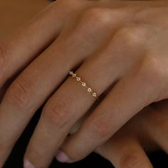 a woman's hand wearing a gold ring with five small white stones on it