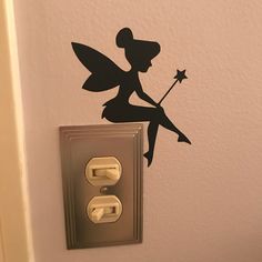 a light switch with a black fairy silhouette on the wall next to an outlet cover