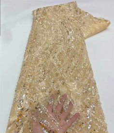 a person's hand on the back of a gold sequinned dress with lots of beads