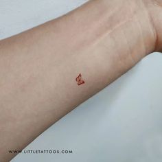 a small red heart tattoo on the arm