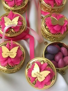 some pink and gold containers filled with chocolates on top of a white table cloth