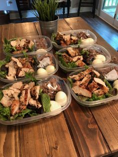 several plastic containers filled with food sitting on top of a wooden table next to a potted plant