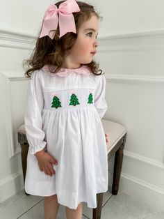 PRE-ORDER - SHIPPING IN NOVEMBER. ESTIMATE DELIVERY DATE PLEASE READ: If you are ordering in stock items along with PRE-ORDER items, they will ship on the PRE-ORDER listing date. If you need the in stock item earlier, please place a separate order.  The perfect little white holiday dress embellished with embroidered Christmas trees and a scalloped sweet pink collar! Clothing Care Instructions: Machine wash gentle. Do not bleach. Tumble dry delicate at low heat. Iron at medium. If the item that y Smocked Christmas Outfits, Winter Christmas Outfits, White Holiday Dress, Smocked Christmas Dresses, Kids Smock, Kids Christmas Dress, Kids Christmas Outfits, Embroidered Christmas, Christmas Outfits