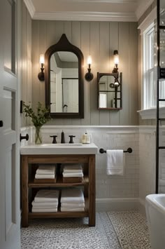 a bathroom with two sinks, mirrors and towels on the rack in front of it