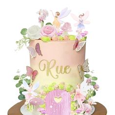 a pink and yellow cake with fairy decorations on top