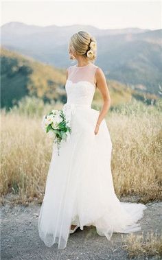 a woman in a wedding dress standing on top of a hill