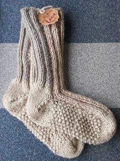 a knitted pair of socks laying on the floor with a tag attached to it