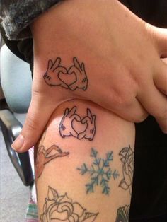 two people holding hands with tattoos on their arms and legs, both showing the same design