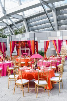 an outdoor event with tables and chairs covered in pink, orange and gold linens