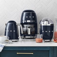 a coffee maker sitting on top of a counter next to cups and orange juices