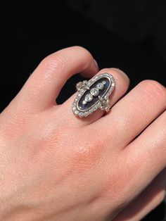 During the Victorian era, navette or “little ship” rings were highly en vogue, and were the perfect statement pieces for elegant nights out or celebrations. This rare Art Deco ring emulates the understated glamor of the navette design, creating a gorgeous and memorable silhouette! Crafted circa 1920’s in 18 carat white gold, this ring features a truly unique synthetic blue topaz gem with a smooth, flat cut. Just look at that hue! The dimensions of color in this topaz is remarkable, and there is White Gold Enamel Ring For Formal Occasions, Diamond Enamel Ring With Diamond Accents For Anniversary, Elegant Brilliant Cut Diamond Enamel Ring, Elegant Enamel Diamond Ring With Brilliant Cut, Luxury Marquise Gemstone Diamond Ring, Elegant Diamond Enamel Ring For Anniversary, Elegant Enamel Ring With Diamond Accents, Art Deco Oval Rings With Rose Cut Diamonds, Oval Art Deco Hallmarked Diamond Ring