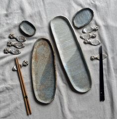 an assortment of objects are laid out on a bed with white sheets and black chopsticks