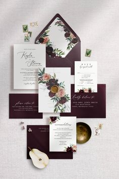 the wedding stationery is laid out on top of each other, with flowers and foliage